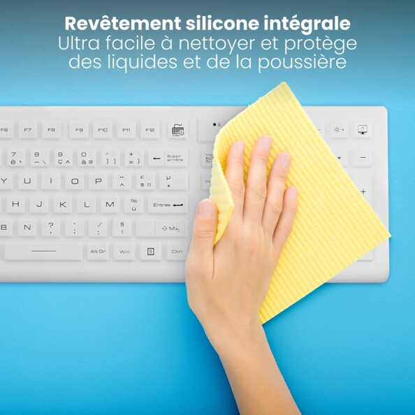 Vue rapprochée du dessus sur le revêtement en silicone intégral du clavier médical AZERTY français avec pavé numérique avec une main qui l'essuie avec un chiffon jaune