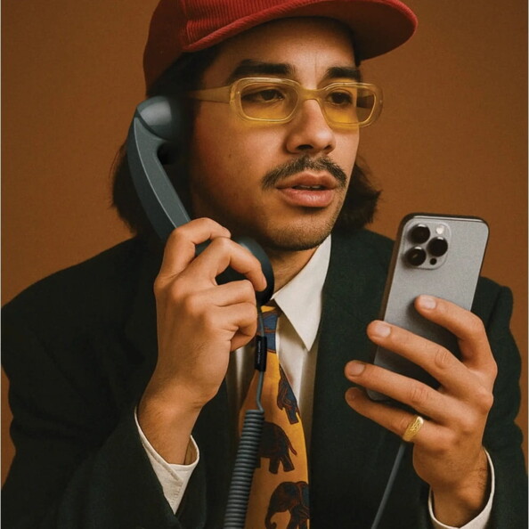 Homme stylisé tenant un combiné rétro gris et un smartphone moderne sur fond brun