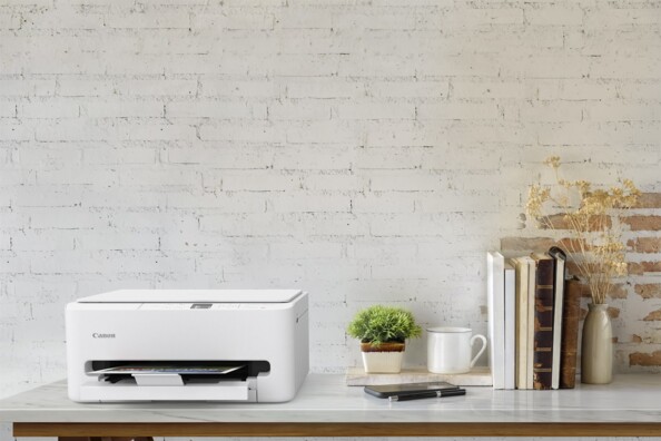 Imprimante Canon PIXMA blanche dans un bureau moderne avec livres, plante et tasse sur étagère