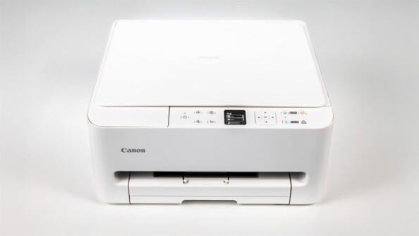 Imprimante Canon PIXMA blanche sur fond blanc avec capot scanner ouvert et page couleur en cours d’impression
