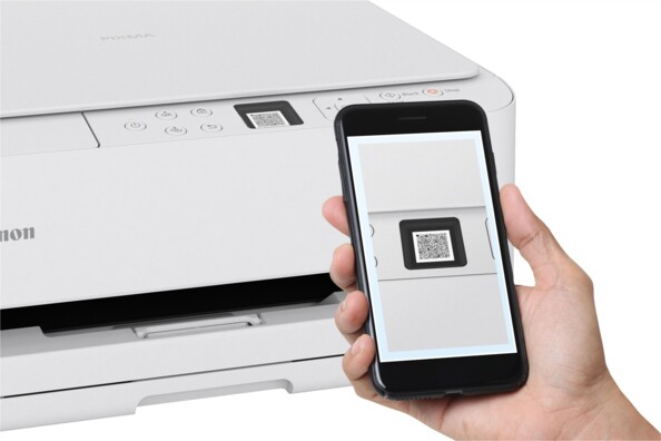 Main tenant un smartphone scannant le QR code de l’imprimante Canon PIXMA pour la configuration Wi-Fi