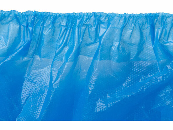 Gros plan d’une surchaussure jetable bleue avec élastique froncé et texture gaufrée