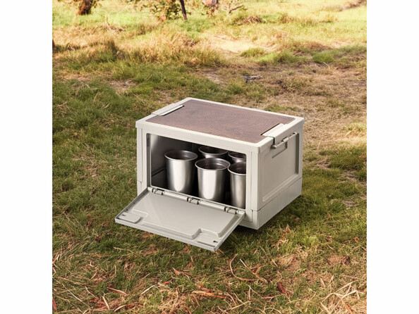 Caisse de rangement pliable posée au sol en extérieur avec gobelet en inox à l'intérieur