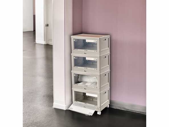 Mise en situation de quatre boîtes de rangement empilées sur quatre roues et installées dans un coin