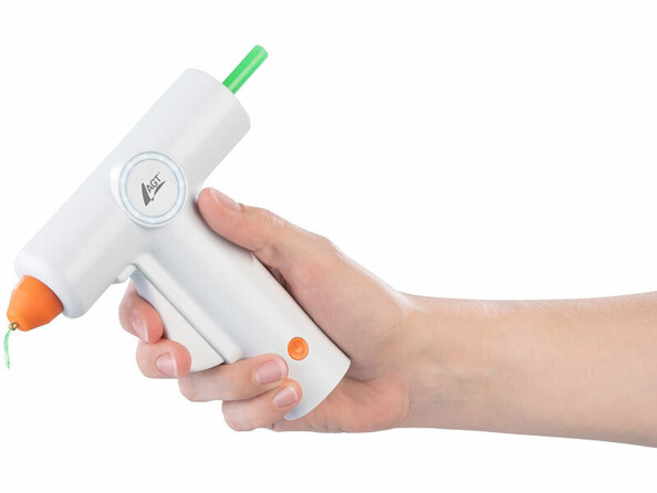 Pistolet à colle sans fil rechargeable tenu en main avec baton de colle verte inséré