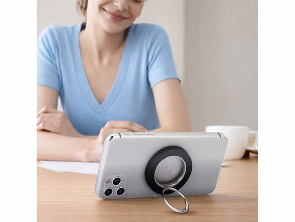 Support magnétique rotatif compatible Magsafe pour smartphone collé à l'arrière d'un smartphone posé sur un bureau devant une femme