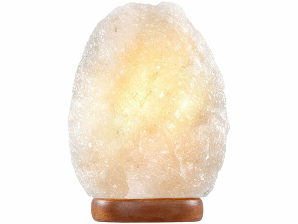 Lampe de sel en cristal rose pâle éclairée, texture rugueuse et brillante, sur base ovale en bois brun