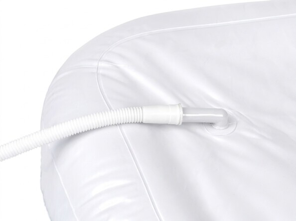 Gros plan sur le raccordement du tuyau flexible cannelé blanc sur la paroi du bac à shampoing gonflable