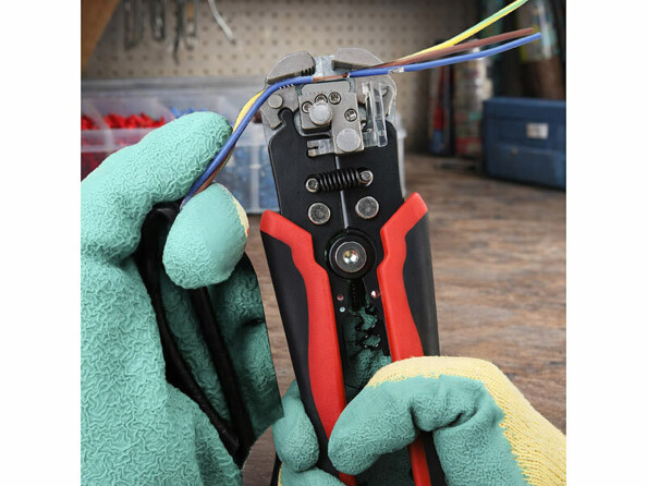 pince à dénuder tenue en main avec des gants mise en situation avec des fils électriques