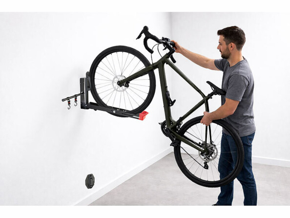 Personne accrochant son vélo sur le support mural orientable