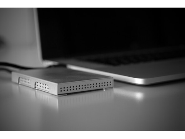 Boîtier Storeva AluSlim U3 gris aluminium posé à côté d'un ordinateur portable