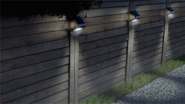 Applique murale solaire Goobay noire, trois luminaires allumés fixés sur une clôture en bois