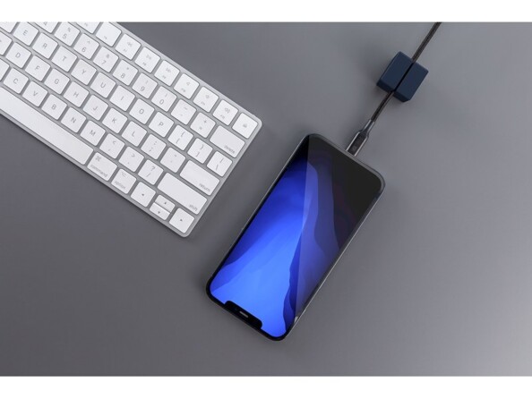 iPhone en cours de chargement par le biais d'un câble coloris noir maintenu droit par un petit passe-câble