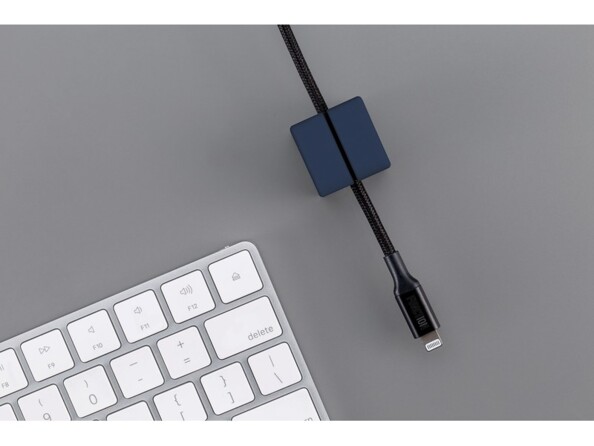 Mise en situation d'un câble lightning noir encastré dans un cube magnétique avec connecteur apparent à côté d'un clavier sans fil