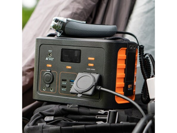 Branchement de multiples appareils électriques dont un rasoir à la batterie externe portable haute capacité Xtorm devant une tente de camping