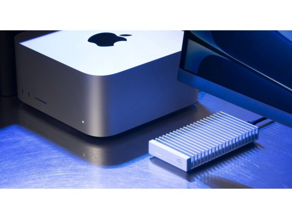 Boîtier USB4 branché par câble USB-C noir à un écran éteint et à un Mac Studio