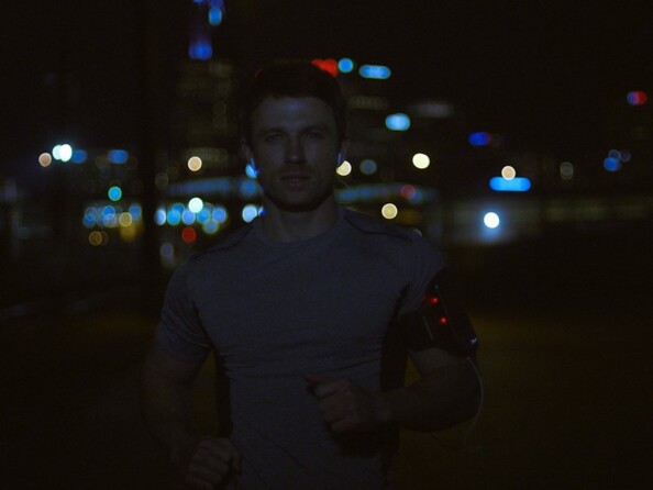 Homme effectuant son jogging quotidien de nuit avec le brassard lumineux pour téléphone autour du biceps