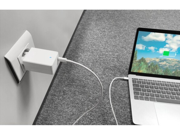 Chargement d'un MacBook posé au sol à l'aide du chargeur secteur Novodio et de son câble de chargement USB-C à une prise de courant murale