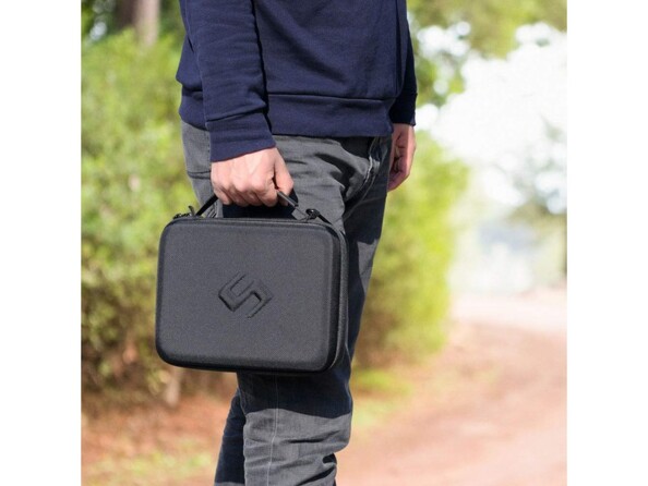 Mise en situation d'un homme portant la valisette de son gimbal dans la main droite pendant qu'il marche en extérieur