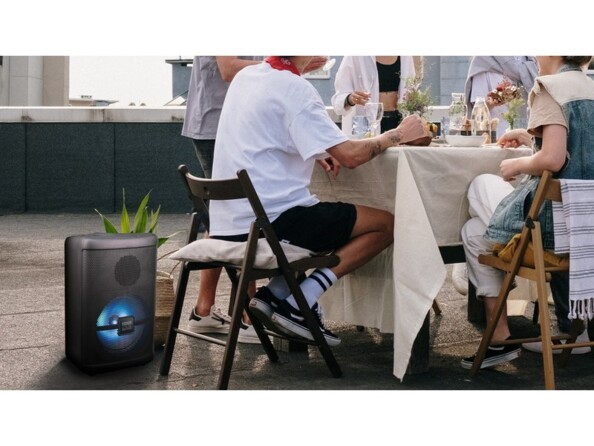 Utilisation de l'enceinte stéro bluetooth sur une terrasse comme système sonore d'ambiance pendant un repas de famille