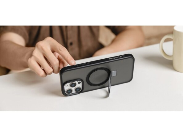 Mise en situation du positionnement vertical d'un iPhone sur support MagSafe 2 en 1 sur une table basse de salon devant une personne scrollant sur l'écran avec une tasse à côté