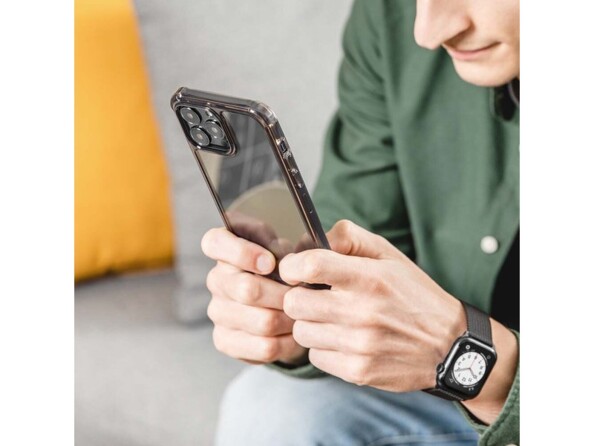 Mise en situation d'un homme assis tenant dans ses deux mains un iPhone noir avec coque transparente