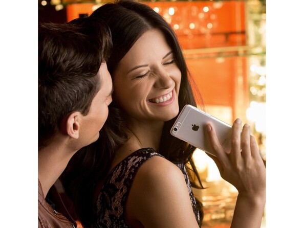 Jeune femme souriante avec iPhone à la main et son petit copain derrière elle