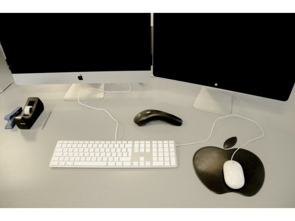 Bureau avec deux écrans Mac, rouleau de scotch, interphone, souris blanche filaire sur tapis en forme de logo Apple noir et clavier fin AZERTY LMP
