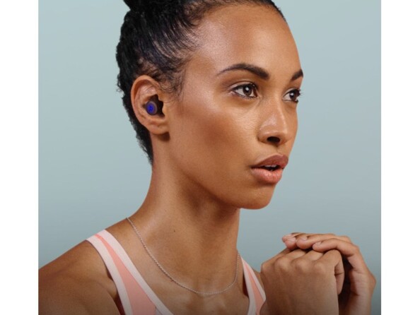 Femme métisse concentrée les poings devant avec les écouteurs sans fil coloris noir dans les oreilles