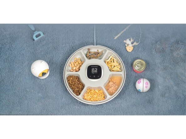 Vue du dessus sur la gamelle NutriSpin ouverte avec 6 petites récipients remplis de nourriture sèche ou humide à côté de jouets et d'ustensiles de toilettage pour chien et chat