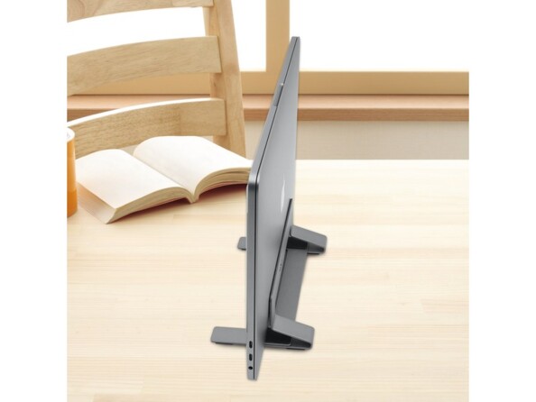 Mise en situation du support Macally VSTAND avec PC fermé à l'intérieur sur une table en bois à côté d'un livre ouvert