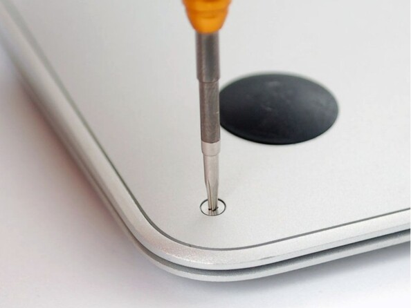 Mise en situation du dévissage d'une vis Pentalobe sur le capot inférieur d'un MacBook à l'aide de la pointe Pentalobe du tournevis Pentalobe P5 1,2 mm MacWay coloris jaune