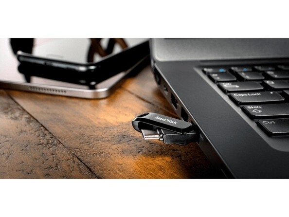 Clé USB double connecteur branchée au port USB-A d'une ordinateur portable posé sur une surface en bois ancien