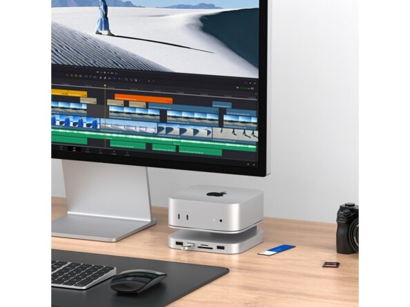 Mise en situation d'un boîtier Mac Mini M4 posé sur la station d'accueil MacWay à côté d'un Mac et de divers périphériques sur un bureau en bois clair