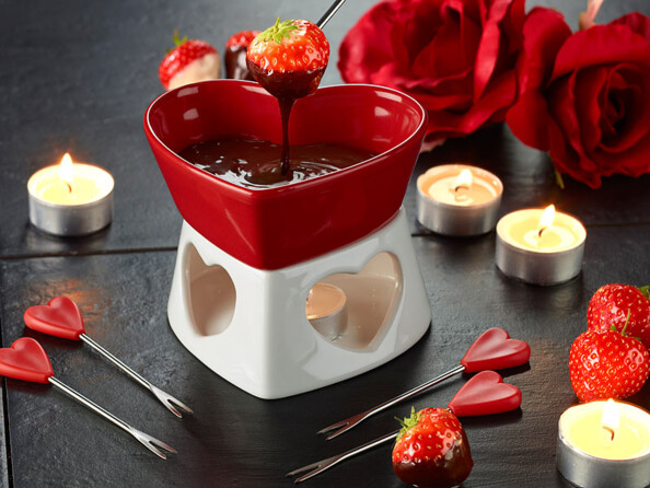 Appareil céramique pour fondue au chocolat posé sur un table avec fourchettes et bougies