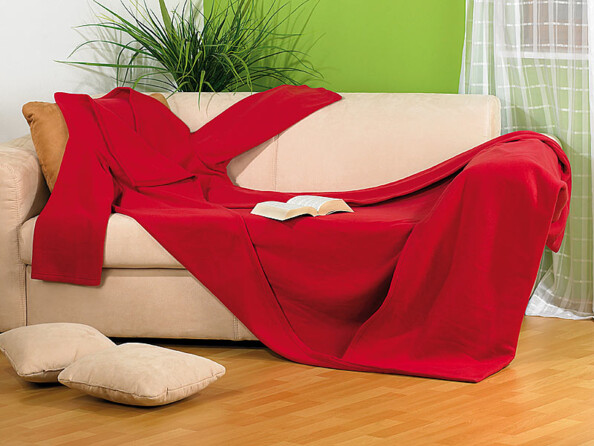 Plaid couverture polaire douce avec ouvertures pour les bras posé avec un livre sur un canapé de salon