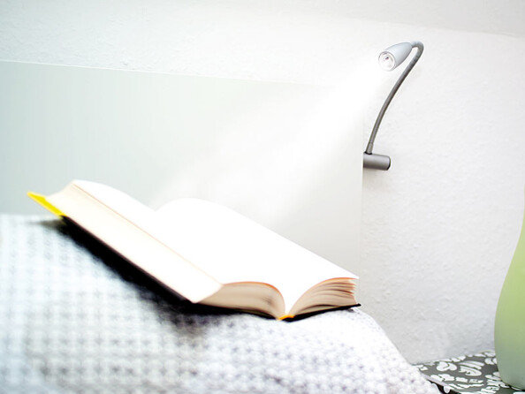 Spot LED dirigeable de lecture fixé à un lit et utilisé pour éclairer un livre