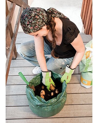 Femme en action arrosant un sac de culture rempli avec pistolet d'arrosage
