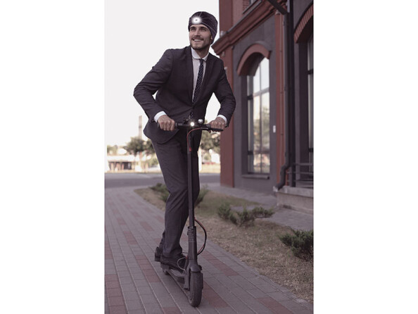 Bonnet mixte à LED avant et arrière mise en situation avec une personne sur une trottinette