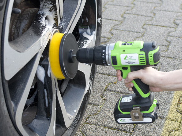 Main tenant une perceuse avec brosse rotative AGT et nettoyant les jantes d'un véhicule