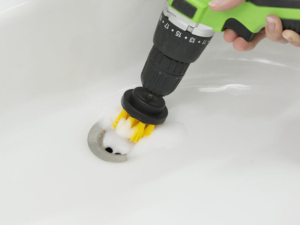 Nettoyage de l'orifice d'écoulement d'un lavabo avec le petit embout rond fixé sur une perceuse-visseuse