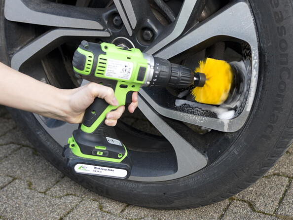 Mise en situation d'une personne nettoyant les jantes de son véhicule avec la brosse type ogive fixée à une perceuse-visseuse
