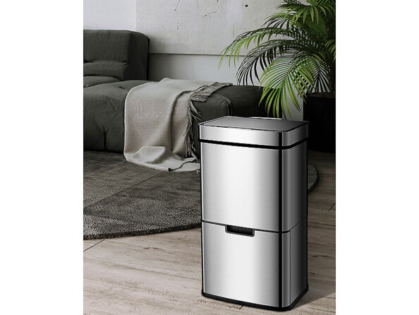 Poubelle grise design installée dans un salon devant un canapé et une plante verte