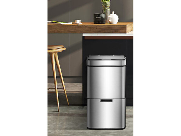 Poubelle de tri placée devant un bar îlot central en bois dans une cuisine moderne