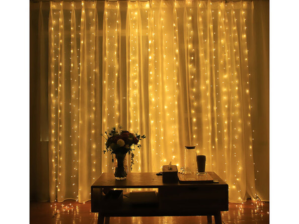 Rideau lumineux à LED blanches accroché devant une fenêtre.