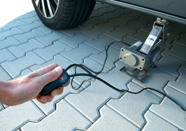 Cric électrique avec câble de connexion 12V, télécommande intégrée et coffret de transport.