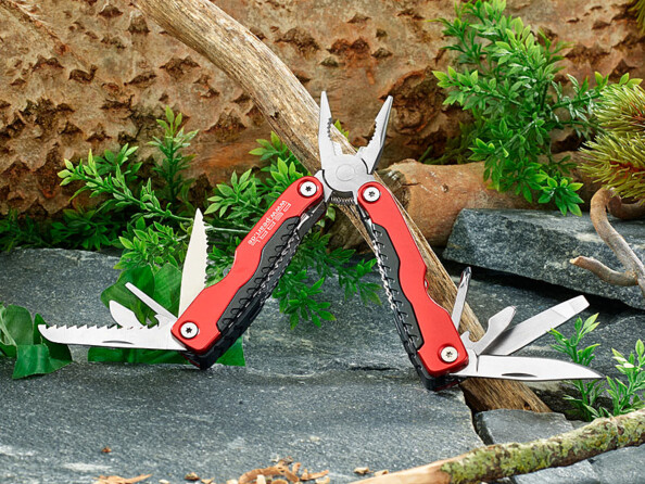 Pince multifonction pliable ouverte et posé sur une pierre à l'extérieur