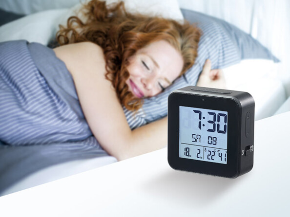 réveil radio-piloté posé sur une table de nuit à côté d'une femme qui dort