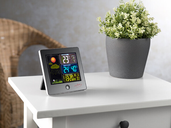 Station météo avec grand écran LCD posé sur une table dans une maison