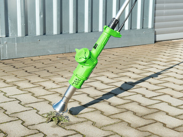 Désherbeur thermique Royal Gardineer utilisé pour éliminer les mauvaises herbes sur un chemin pavé.
